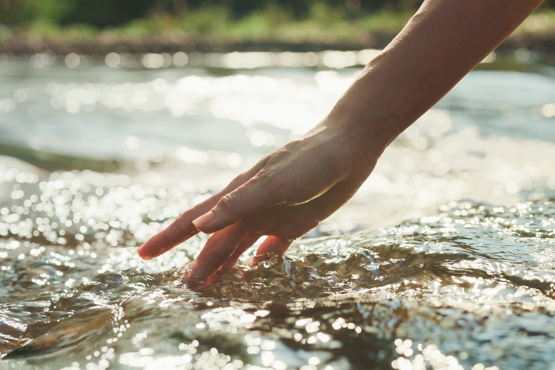 Eine Hand vor fließendem Wasser.